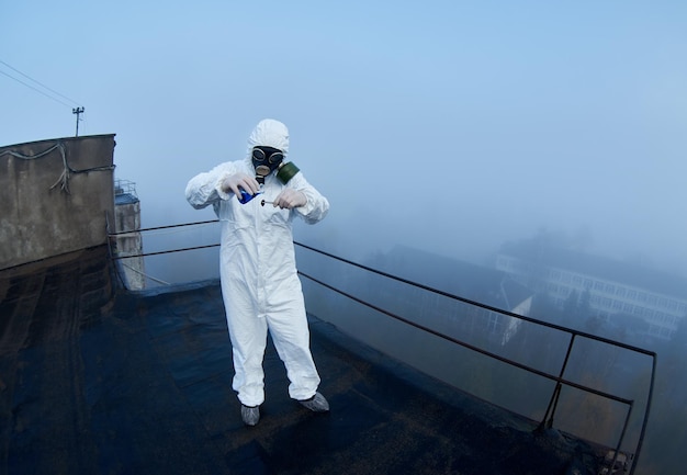 Worker scientist wearing protective coverall and gas mask doing ecological tests on the roof