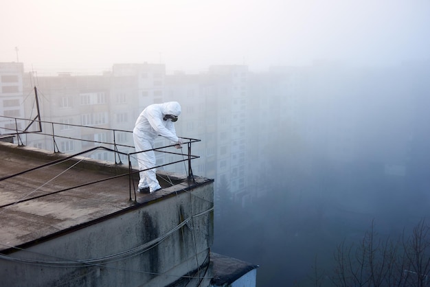 Рабочий ученый в защитном комбинезоне и противогазе проводит экологические испытания на крыше