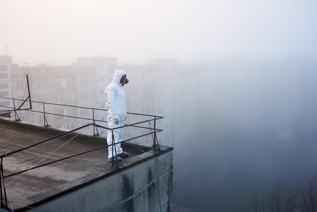 Worker scientist wearing protective coverall and gas mask doing ecological tests on the roof