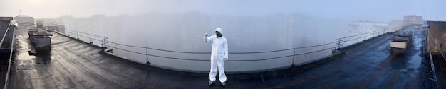 Worker scientist wearing protective coverall and gas mask doing ecological tests on the roof