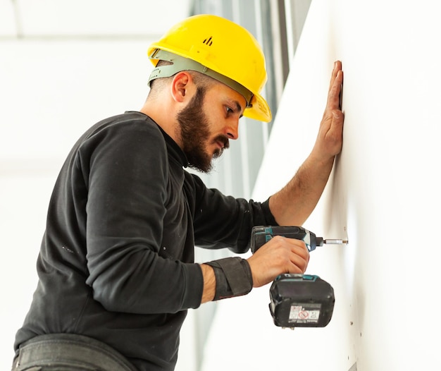 Worker screws plasterboard panels