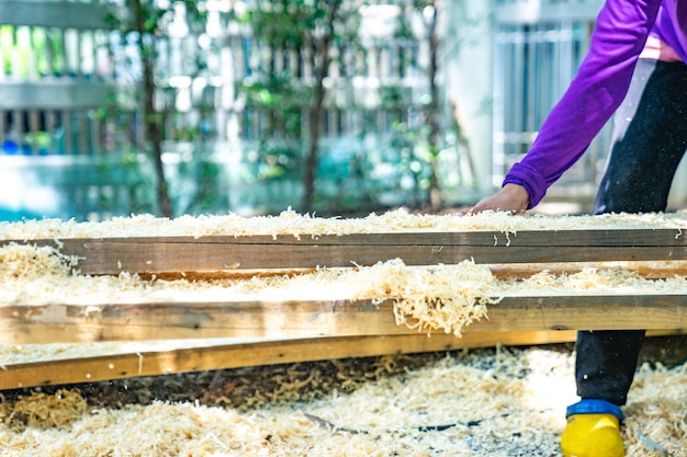 Worker scrubs the big long wood plate with polishing machine in the garden