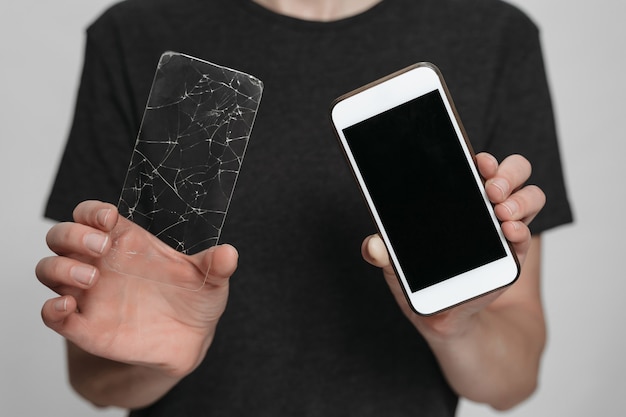 Foto operaio del centro servizi che tiene in mano lo smartphone e la protezione dello schermo rotto