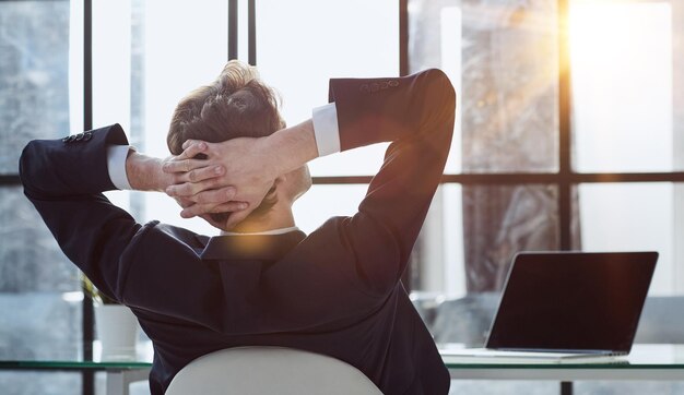 Photo worker sitting in office with hands behind his head