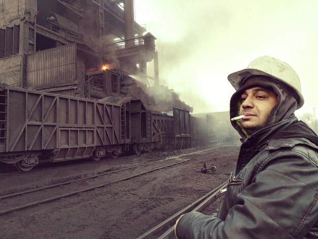 Photo worker smoking cigarette by railroad tracks