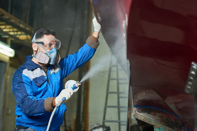 Worker Spray Painting Boats in Workshop