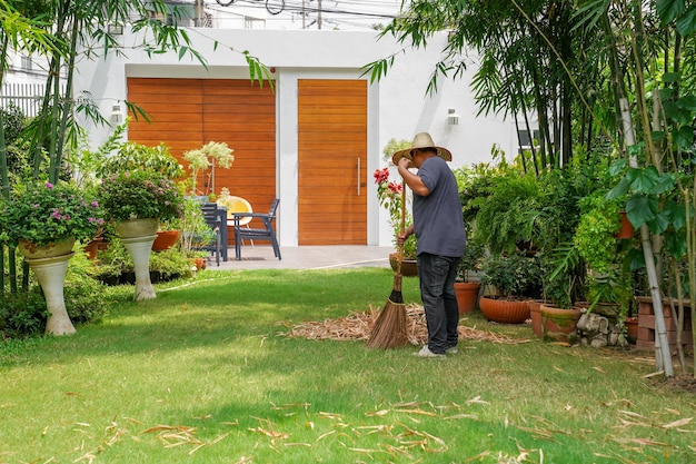 Worker sweeps dry leafs in garden