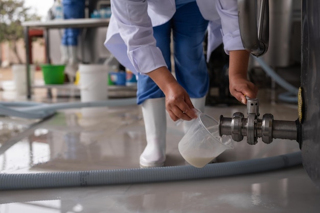 Worker taking milk samples from a tank