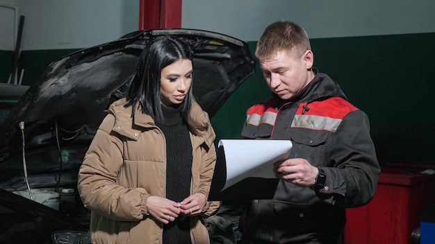 Worker talks to client showing cost list near broken car