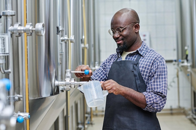 Worker tasting beer after brewing