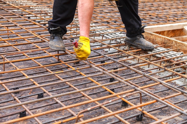 Worker ties steel reinforcing bars with wire.