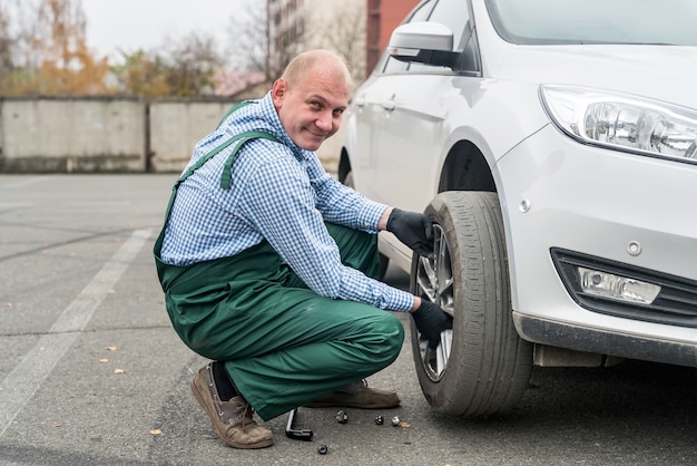 Photo worker in uniform fixing changed wheel in car