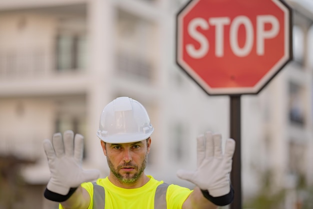 Foto lavoratore in uniforme che gesturing ferma il costruttore serio con il costruttore di segnali stradali di stop con il gesto di stop no ha