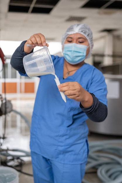 Worker in uniform taking samples in a dairy industry
