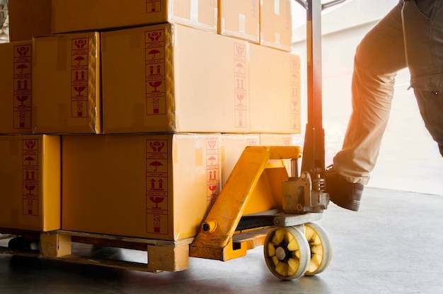 Photo worker unloading shipment goods with hand pallet truck