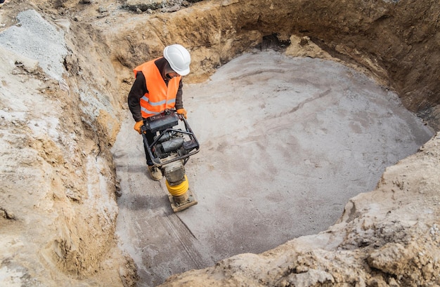 Worker uses a portable vibration rammer at construction of a power transmission substation