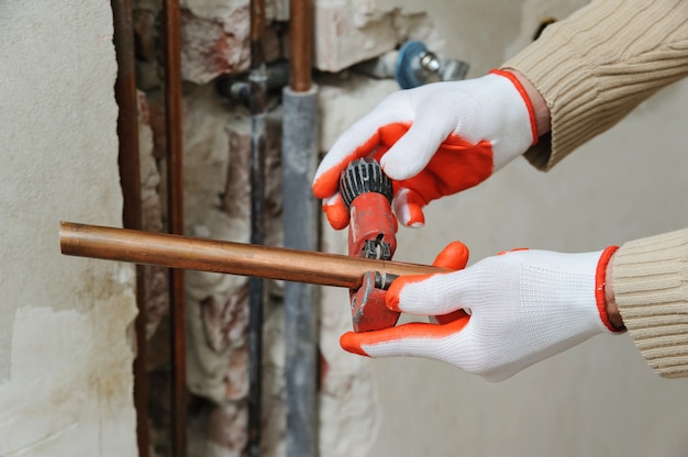 Worker using copper pipe cutter to cut the pipes