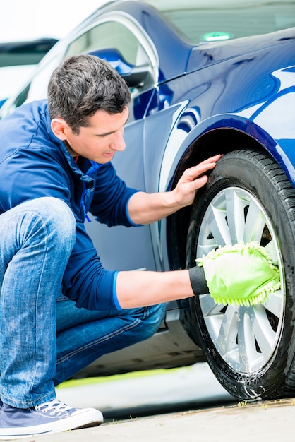 Worker using microfiber car wash mitt for cleaning rim 