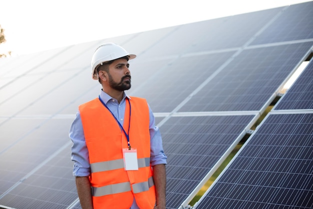 Worker in a vest and helmet stands on a solar station