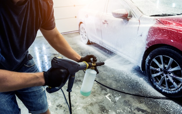 Outdoor Car wash worker Cleaning stains with foam soap. Leave space to  write a description of the message. Stock Photo
