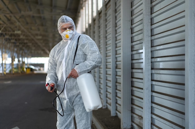 Worker wearing protective suit disinfection gear disinfect\
surface public place parking