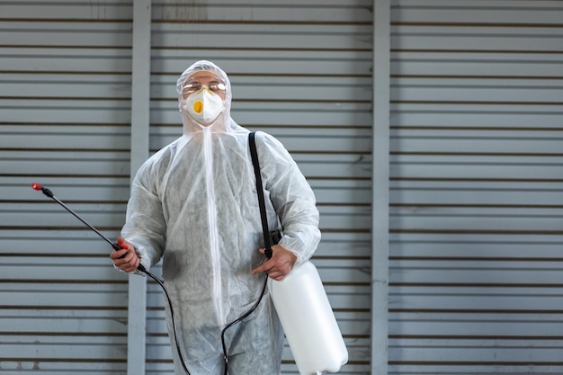 Worker wearing protective suit disinfection gear disinfect\
surface public place