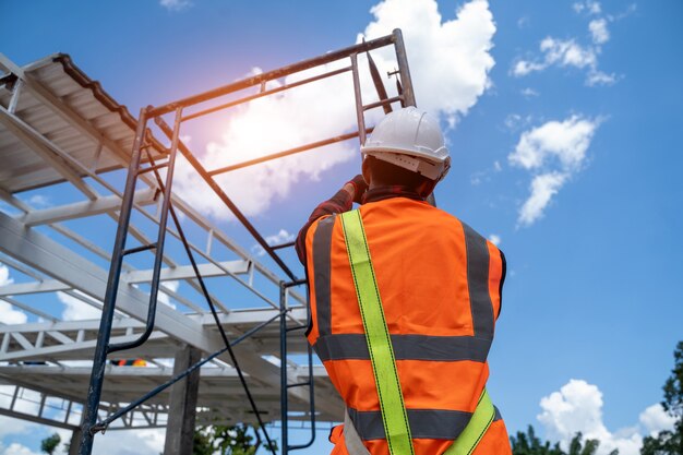 Worker wearing safety equipment and safety belts working on\
height at construction site.