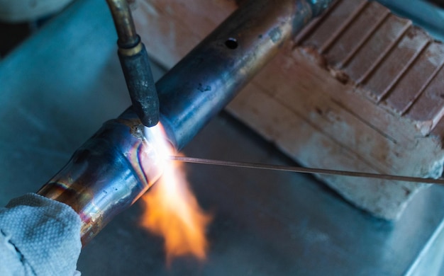 a worker welds copper pipes with a gas burner