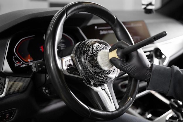 Worker wipes the steering wheel of the car dry cleaning and interior washing Detailing studio