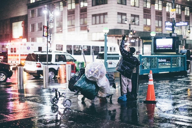 worker with garbage trolley standing on city street during rainy season