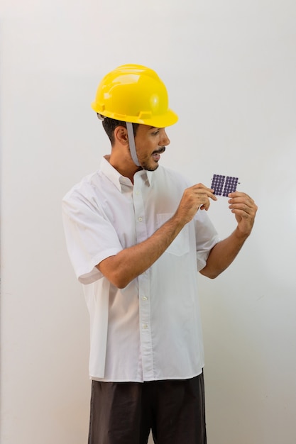 Operaio con il casco che tiene un pannello solare fotovoltaico isolato su priorità bassa bianca.