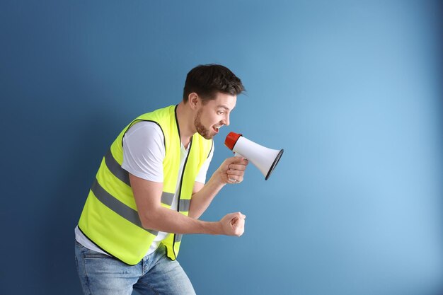 Worker with megaphone on color background