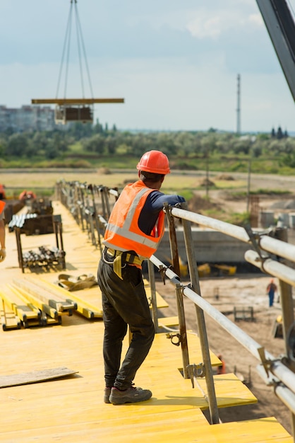 Фото Рабочий в защитной каске на строительной площадке транспортного моста
