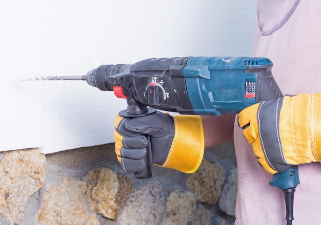 Worker with rockdrill warms the wall