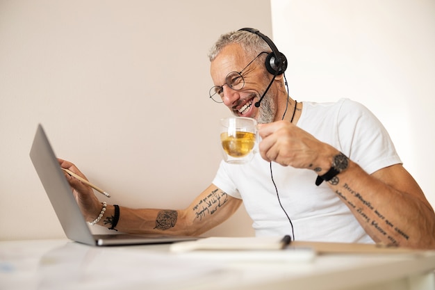 Worker with tattooed arms drinking tea and touching the screen