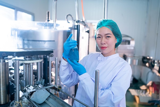 Worker working in drink factory at conveyor belt with fruit\
juice glass bottled in production line