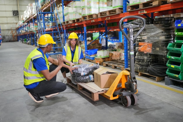 worker working in large warehouse holding paper chart check list checking the material compare with the boxes wrapped with plastic keep on wooden pallet ready to ship to customer