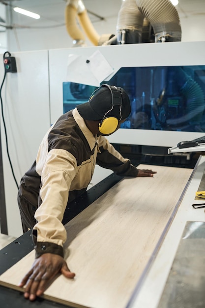 Worker working on machine for sawing wood