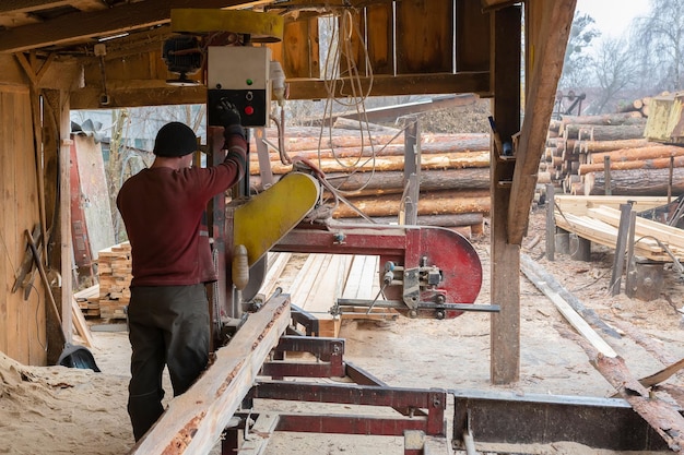 A worker works on sawmill equipment wood processing work\
process timber industry