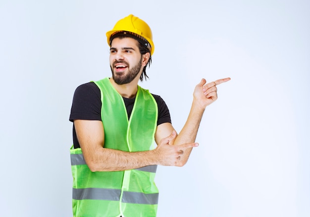 Worker in yellow helmet pointing to the right side.