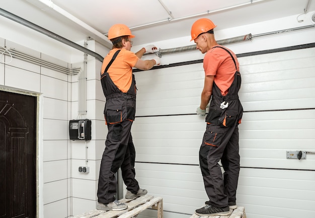 The workers are installing lift gates in the garage.