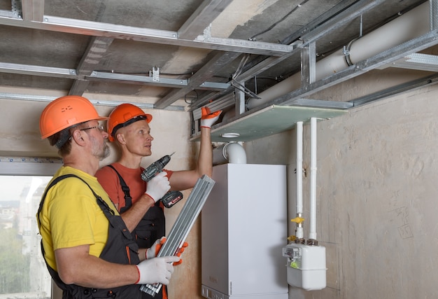 Workers are mounting a complex frame for drywall on the ceiling