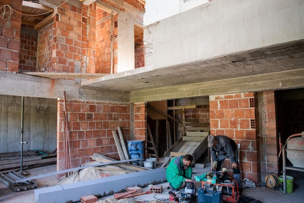 workers on construction site interior of new two levels apartment with windows and red brick walls  construction site in progress to new house