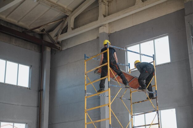 Workers of the enterprise in protective helmets adjust and\
repair the metal crane