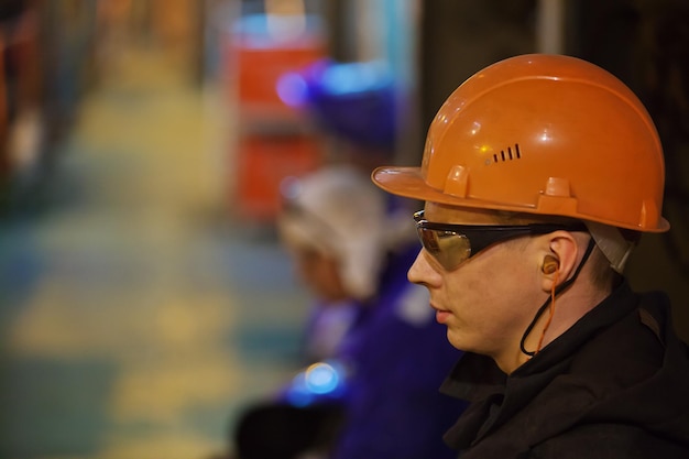 Photo workers fitters and welders in protective clothing and a helmet working in the operating industrial facilities