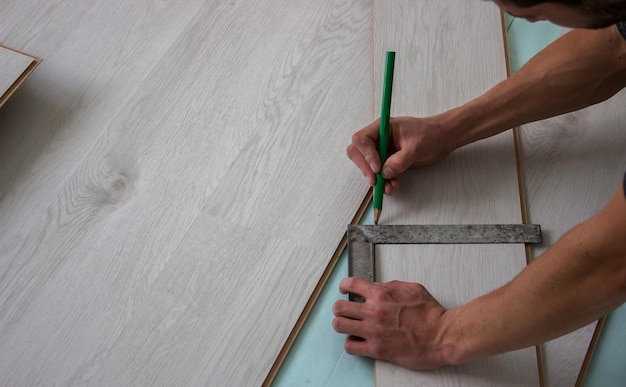 Workers' hands install a wooden laminate floor. Home renovation with wooden floors with measurements. selective focus