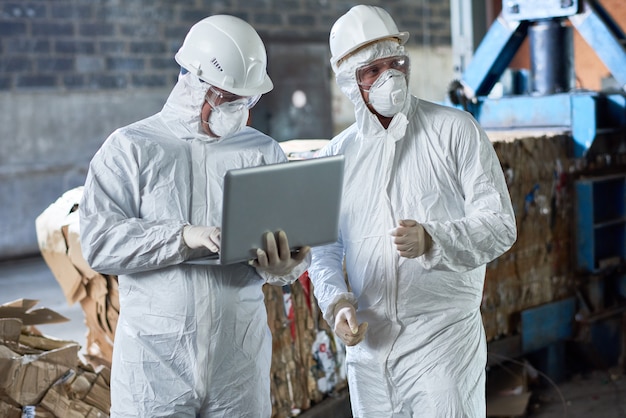 Workers in hazmat suits at modern recycling factory