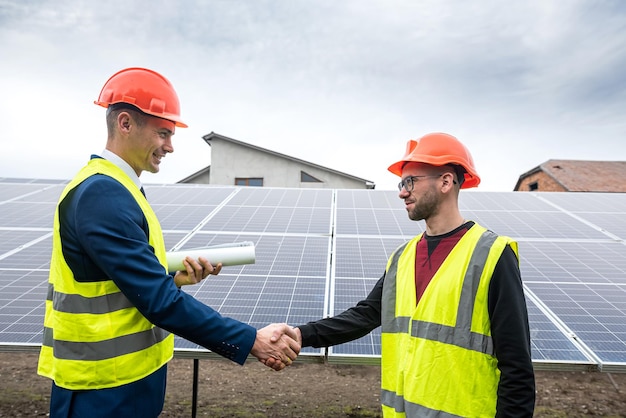 Workers on installation of solar economical panels shake hands after work The concept of solar panels