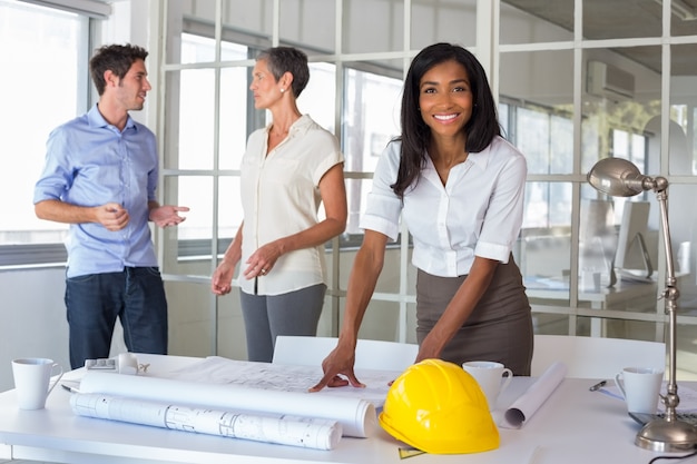 Workers loooking over plans and smiling at camera