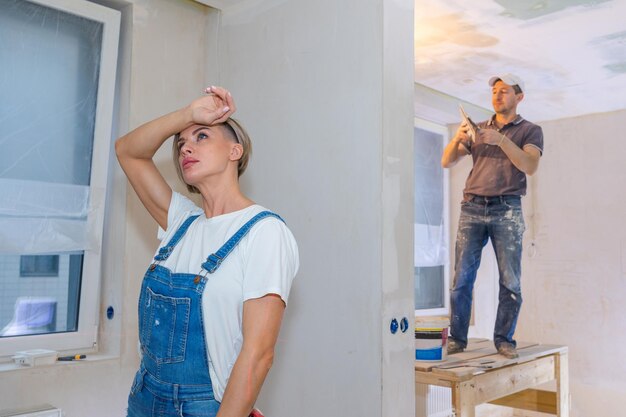 Workers make repairs in new apartment Woman and man plaster walls and ceilings